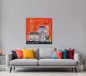 Preview: Wandbild Bonn-City in Orange über grauem Sofa mit bunten Kissen vor heller Wand.